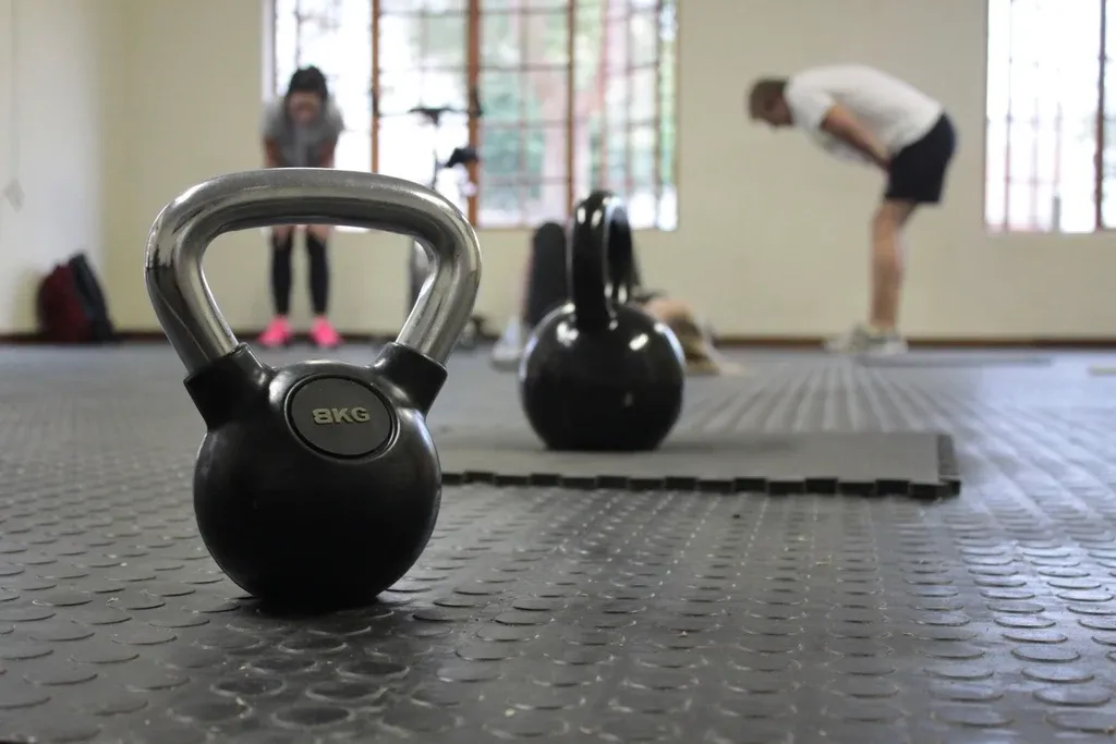 A kettlebell on the gym floor with people warming up behind it